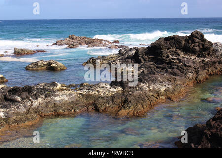 Kleine Wellen auf einem vulkanischen Felsen outcroppings am Hookipa Beach, Maui, am Anfang der Straße nach Hana Stockfoto