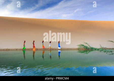 Cham Frauen in traditioneller Kleidung gehen über Sanddünen zu Sammeln von Wasser in der Nähe von Phan Rang, Vietnam. Viele Leute halten Cham Stockfoto