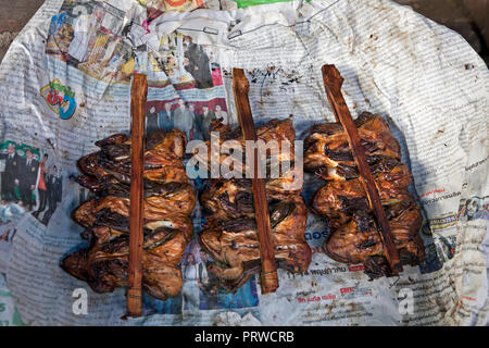 Gebratene grüne Frösche auf Sticks. Eine traditionelle Köstlichkeit auf Eisenbahnschienen Maeklong Markt, Bangkok, Thailand. Stockfoto