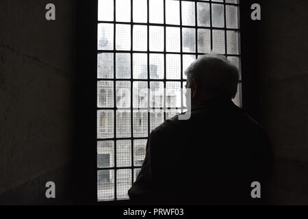 Dunkle Silhouette eines älteren Menschen, durch ein Fenster in der Taufkapelle Pisa, Italien. Die Kathedrale von Pisa kaum Außen gesehen Stockfoto