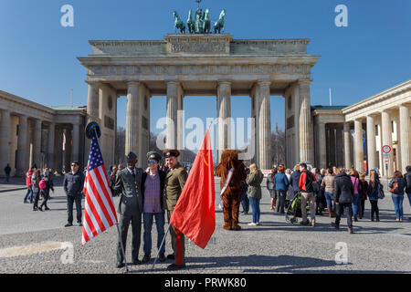 Junge weibliche Touristen mit amerikanischer und russischer Soldat vor Berliner Tor oder Brandenburger Tor posieren. Stockfoto