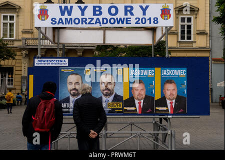 Krakau, Polen. 4. Okt, 2018. Polnische Bürger gesehen werden, da sie sich auf einem Brett mit Informationen über die Kommunalwahlen am Hauptplatz. Am 21. Oktober 2018 polnische Bürger wird für Tausende von Ratsmitgliedern und Bürgermeistern in regionalen, Grafschaft und Pfarrei Wahlen stimmen. Credit: Omar Marques/SOPA Images/ZUMA Draht/Alamy leben Nachrichten Stockfoto