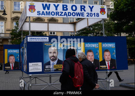 Krakau, Polen. 4. Okt, 2018. Polnische Bürger gesehen werden, da sie sich auf einem Brett mit Informationen über die Kommunalwahlen am Hauptplatz. Am 21. Oktober 2018 polnische Bürger wird für Tausende von Ratsmitgliedern und Bürgermeistern in regionalen, Grafschaft und Pfarrei Wahlen stimmen. Credit: Omar Marques/SOPA Images/ZUMA Draht/Alamy leben Nachrichten Stockfoto