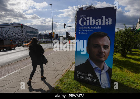 Krakau, Polen. 4. Okt, 2018. Eine Frau geht durch ein Plakat mit einem Kandidaten für die Bürgermeister von Krakau. Am 21. Oktober 2018 polnische Bürger wird für Tausende von Ratsmitgliedern und Bürgermeistern in regionalen, Grafschaft und Pfarrei Wahlen stimmen. Credit: Omar Marques/SOPA Images/ZUMA Draht/Alamy leben Nachrichten Stockfoto