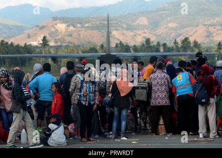 Palu, Indonesien. 4. Okt, 2018. Die Menschen warten ein militärisches Flugzeug zu dem Erdbeben und dem Tsunami-geschädigte Stadt Palu, Indonesien am 4. Oktober 2018 zu verlassen. Die Zahl der Todesopfer von mehreren Beben und ein tsunami in der indonesischen Provinz Zentral-sulawesi auf 1.424 gestiegen, während die Suche und Bergung durch den schlechten Zugang zu den am stärksten betroffenen Gebieten behindert war, ein Beamter sagte am Donnerstag. Credit: Agung Kuncahya B./Xinhua/Alamy leben Nachrichten Stockfoto