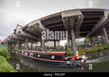 Oldbury, West Midlands, UK. 5. Oktober, 2018. Ein Kanal Boot fährt durch das Gerüst unter dem Oldbury Viadukt Abschnitt der Autobahn M5 entfernt. Autobahnen England haben gesagt, dass wesentliche Reparaturen zwischen den Anschlussstellen 1 und 2 wird jetzt nicht bis zum Frühjahr 2019 Aufgrund des außergewöhnlichen heiße Wetter in diesem Sommer beenden. Die Nachricht ist nicht von Autofahrern, die zu langen Verzögerungen aufgrund Wegschliessen und Geschwindigkeitsbeschränkung von 30 km/h auf dieser Strecke ertragen begrüßt. Der Viadukt Oldbury M5 trägt 120.000 Fahrzeuge pro Tag. Peter Lopeman/Alamy leben Nachrichten Stockfoto