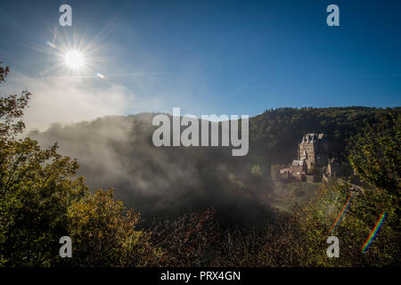 05 Oktober 2018, Rheinland-Pfalz, Wierschem: Die Sonne herrscht über die letzten Nebel Banken auf der Burg Eltz, während die Blätter der Bäume herbstliche drehen. In den kommenden Tagen die Temperaturen bis 23 Grad erreichen. Die mittelalterliche Burganlage ist eine der wichtigsten Sehenswürdigkeiten in Rheinland-Pfalz und ist der Ausgangspunkt für zahlreiche Wanderwege durch die Eifel. Foto: Boris Roessler/dpa Stockfoto