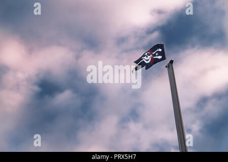 Piraten Flagge am Mast gegen die drastischen, blau rot bewölkter Himmel Stockfoto