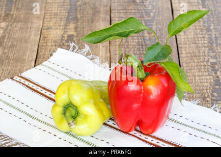 Nur reife rote und gelbe Paprika liegen auf dem Handtuch mit Ornament auf Holzbrettern abgeholt. Bulgarische oder Paprika. Stockfoto