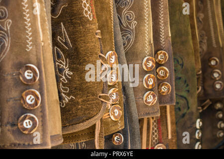 Traditionelle österreichische und bayerische Lederhosen (Lederhose). Verschiedene Lederhosen hängen in einer Reihe. Nahaufnahme der Tasten. Stockfoto