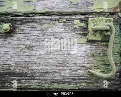 Eine alte rostige grüne Haken hängend an altes verwittertes Holz Stockfoto
