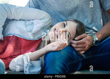 Frau entspannend auf dem Schoß des Mannes Stockfoto