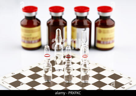 Ampullen auf Schachbrett, Flaschen mit Medizin. Stockfoto