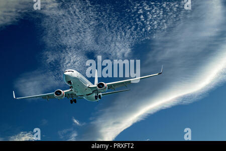 Eine künstlerische skyscape Ansicht eines kommerziellen Passagierflugzeugen fliegen closeup in einem pulsierenden blauen Himmel mit hellen, weißen Wolken -. Stockfoto