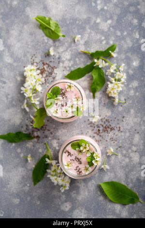 Overhead Schuß von zwei Gläser mit rosa Joghurt garniert mit Minze und weißen Blütenblättern Stockfoto