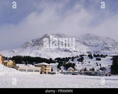 Alpine Village San Bernardino im Winter, mit nadelbaumbaum Wald und schneebedeckten Berge im Hintergrund, Graubünden, Schweiz Stockfoto