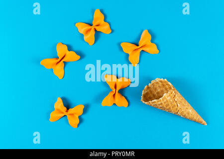 Kreative Sommer Layout aus Eis, Waffeln und farbigen Nudeln Grieß Papillon auf hellen blauen Hintergrund. Minimalen Begriff Stockfoto