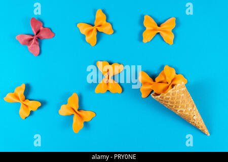 Kreative Sommer Layout aus Eis, Waffeln und farbigen Nudeln Grieß Papillon auf hellen blauen Hintergrund. Minimalen Begriff Stockfoto