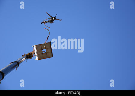 Bungee Jumping von einem 50 Meter hohen Kran springen während Sofia Extreme Sports Festival. Aus dem Boden mann Springen von einer Plattform hoch in den blauen Himmel gesehen Stockfoto