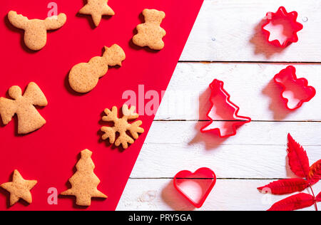 Rote und weiße Weihnachten backen Konzept mit Ingwer Cookies in verschiedenen Xmas Formen und Förmchen. Minimalistische Weihnachten Kontext. Stockfoto