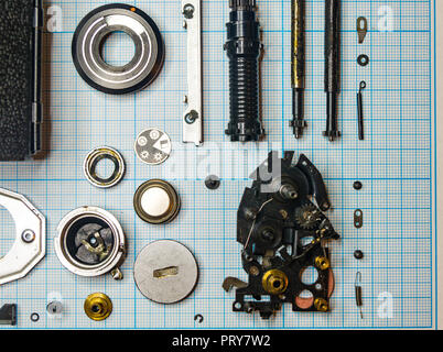 Teile sind vollständig demontiert alten retro Film SLR Kamera auf Millimeterpapier, close-up Stockfoto