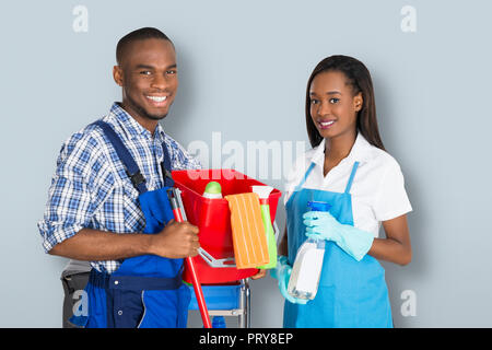 Portrait von lächelnden Afrikanischen Männlichen und Weiblichen Hausmeister mit der Reinigung der Ausrüstung Stockfoto