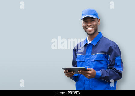 Portrait eines glücklichen jungen afrikanischen Elektriker Holding Handy Stockfoto