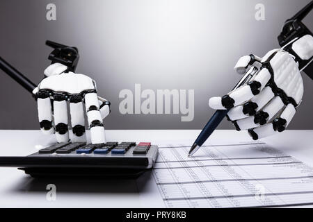 Nahaufnahme der Roboter Prüfung Finanzbericht mit dem Rechner auf dem Schreibtisch Stockfoto