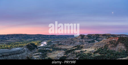 Die Little Missouri River River Bend Blicken auf Theodore Roosevelt National Park North Unit, bei Sonnenaufgang mit dem Mond hinter diesigen Wolken gesehen. Stockfoto