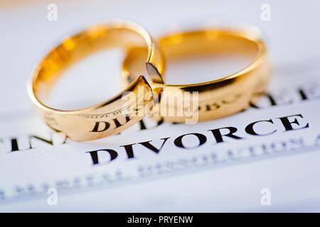 Zwei gebrochene goldene Hochzeit Ringe Scheidungsurteil Dokument. Scheidung und Trennung Konzept Stockfoto