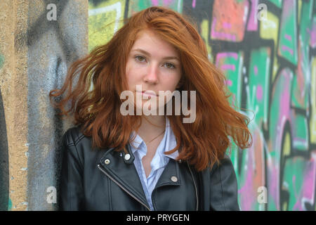 Portrait, rothaarige Mädchen, junge Frau in Leder Jacke vor Graffiti, in Finale Ligure, Riviera di Ponente, Ligurien Stockfoto