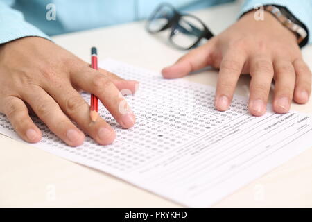 Bild des Menschen Hand auf OME-Blatt mit Bleistift und Gläser auf dem Tisch. Stockfoto