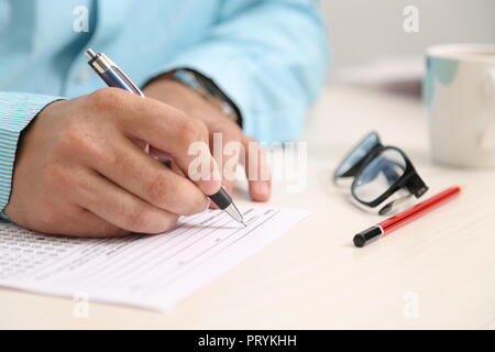 Bild des Menschen, der die Feder. Gläser, Becher, Bleistift und OME-Blatt auf den Tisch. Stockfoto