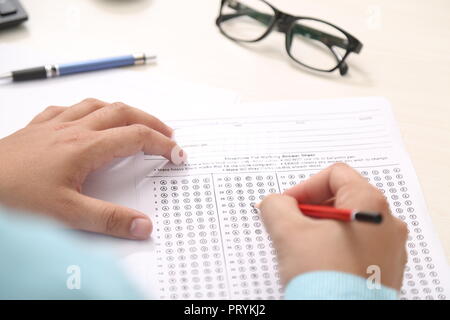 Man füllt OME-Blatt mit Bleistift. Bild von Pen und Gläser auf dem Tisch. Stockfoto