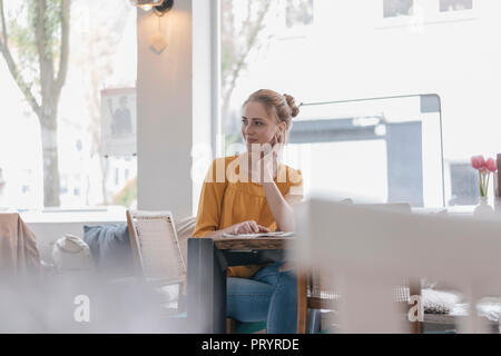 Junge Frau in Coworking Space, lesen Zeitung sitzen Stockfoto