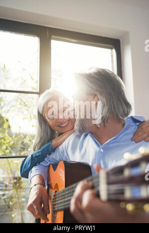 Senior Gitarre spielen und singen laut für seine Frau Stockfoto