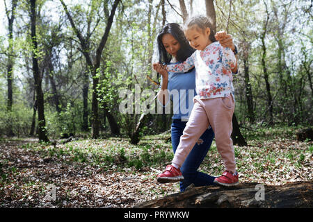 Mutter und Tochter im Park, Mädchen Balancing auf Baumstamm Stockfoto