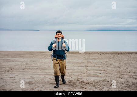 Mann mit Rucksack, Wandern am Strand Stockfoto