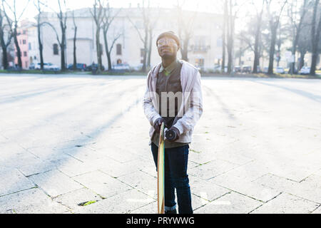 Junge amn mit Skateboard auf städtischen Platz Stockfoto