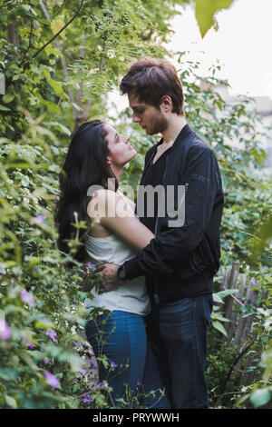 Junges Paar in der Liebe stehen im Gebüsch Stockfoto