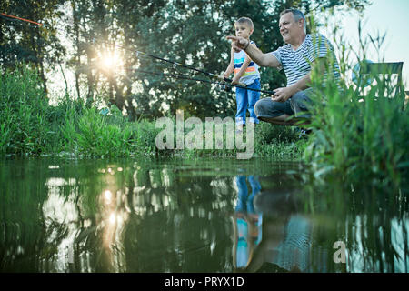 Großvater und Enkel Angeln zusammen am Seeufer Stockfoto