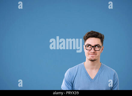 Junge legerer Mann in Gläsern, die Wunder, die plan auf hellen blauen Hintergrund Stockfoto