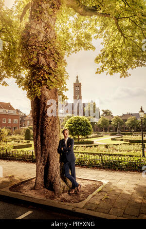 Niederlande, Venlo, Geschäftsmann, lehnte sich an einen Baum Stockfoto