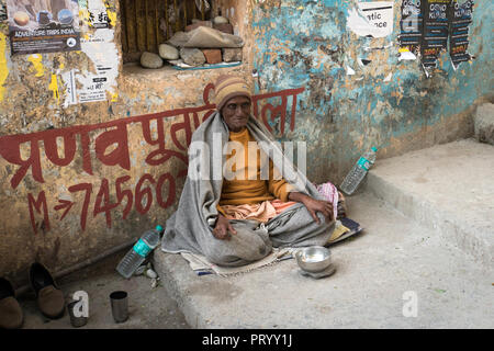 10. Januar 2018. Rishikesh Indien. Ein armer alter Mann sitzt auf einer schmutzigen Straße mit ausgestreckter Hand und bittet um Geld. Stockfoto