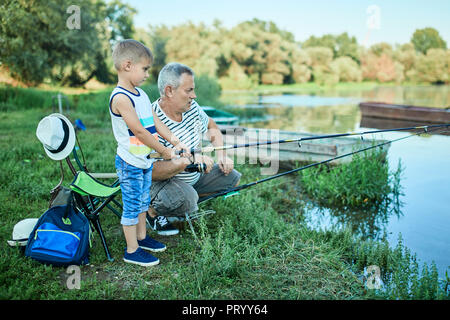 Großvater und Enkel Angeln zusammen am Seeufer Stockfoto