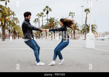 Spanien, Barcelona, glückliches junges Paar, das Spaß an der Promenade mit Palmen Stockfoto