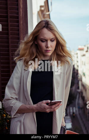 Porträt der blonde junge Frau am Handy suchen Stockfoto