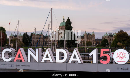 Eine beleuchtete Kanada 150 Zeichen am Hafen in Victoria, British Columbia, Kanada, mit dem Parlament Gebäude im Hintergrund. Stockfoto