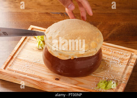 Putuk / Piti - traditionelle armenische Kichererbsen und Lammeintopf in einem Tontopf mit Fladenbrot bedeckt serviert. Stockfoto