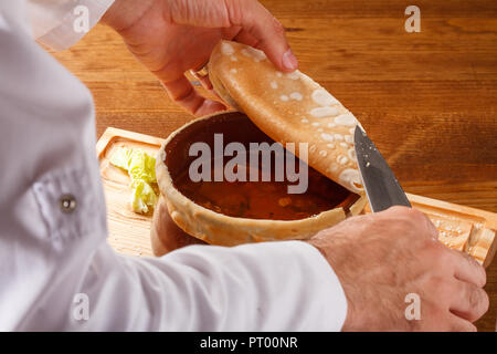 Putuk / Piti - traditionelle armenische Kichererbsen und Lammeintopf in einem Tontopf mit Fladenbrot bedeckt serviert. Stockfoto